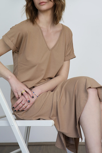 Woman in casual beige stretch cotton midi dress.T shirt dress made from organic cotton. Studio shot.