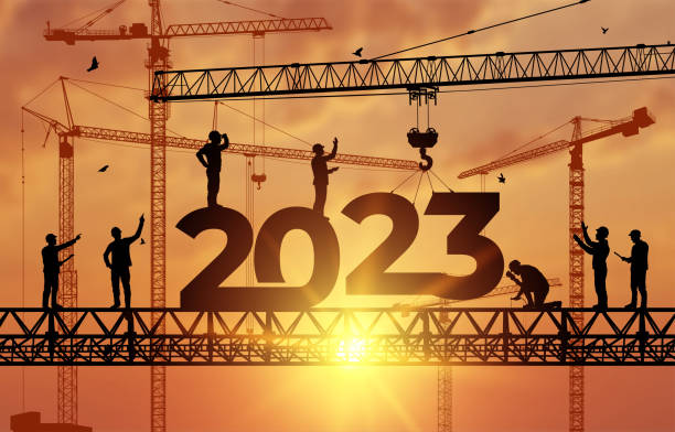 istock Silhouette staff works as a to prepare to welcome the new year 2023. Large construction site, many construction cranes set vector numbers 2023. Construction team sets numbers for New Year 2023. 1367130509