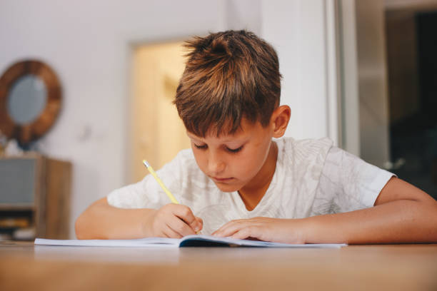 istock A young boy sits at the table, in the dining room, writing in his notebook. 1367137037