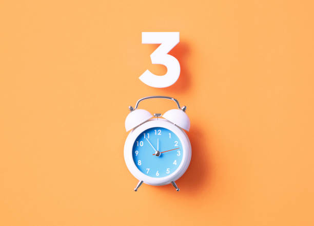 istock Number 3 Sitting Above White Alarm Clock On Orange Background 1367138138