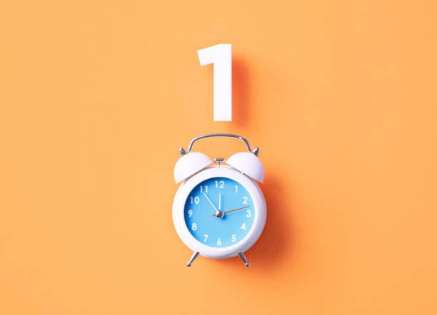 istock Number 1 Sitting Above White Alarm Clock On Orange Background 1367138175