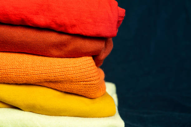istock A stack of multi-colored fabric in warm colors. Background with folded clothes in red and yellow tones with empty space for information. T-shirts of different colors 1367138314