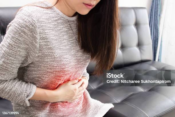Asian Woman Is Stomached And Use Hand Cross Stomach And Feeling Pain With An Inflaming Stock Photo - Download Image Now