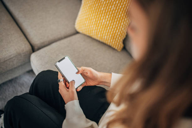istock Young woman using mobile phone while relaxing on the sofa in the livingroom 1367141072