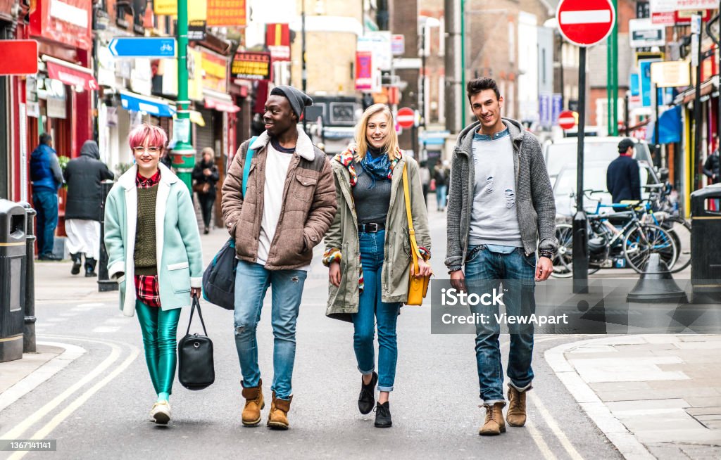 Multicultural students walking on Brick Lane center at Shoreditch London - Life style concept with multi-ethnic young friends on seasonal clothes having fun together outside - Bright vivid filter UK Stock Photo