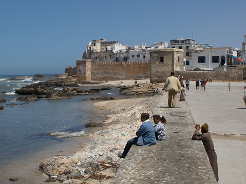 Essaouira, Morocco, August 15, 2012: Group of people next to a wall near the fishing port of Essaouira, Morocco