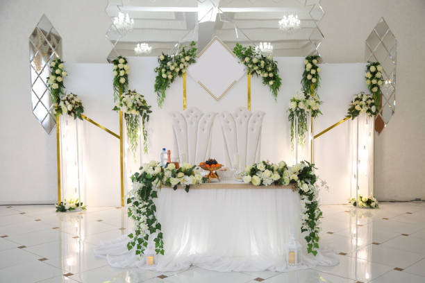 Wedding table of the bride and groom decorated with flowers and greenery on a white background Wedding table of the bride and groom decorated with flowers and greenery on a white background. wedding hall stock pictures, royalty-free photos & images
