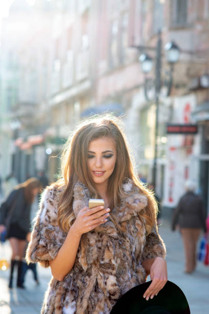 istock Woman outdoors in city street using mobile phone while walking and smiling 1367146698