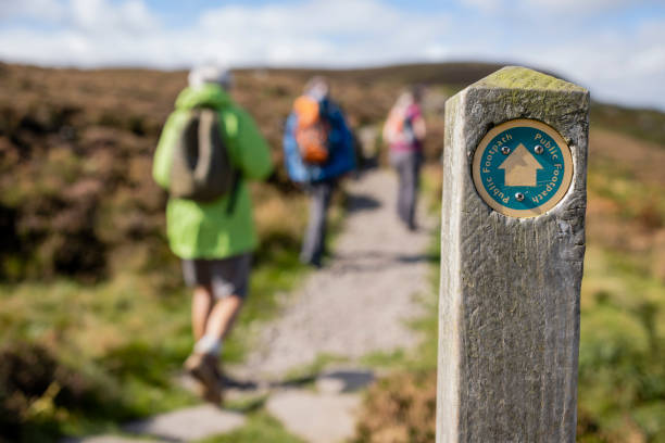 A Public Trail Out of focus shot tourists hiking uphill in Rothbury, Northumberland. The trail post is at the forefront of the shot and is the main focus. hiking sign stock pictures, royalty-free photos & images