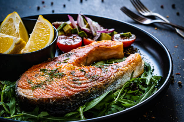 istock Fried salmon steak and fresh vegetables on black wooden background 1367149965