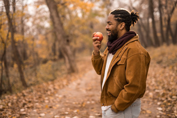 istock Happy young African American man eating an apple while on a walk outdoors in nature. 1367150065