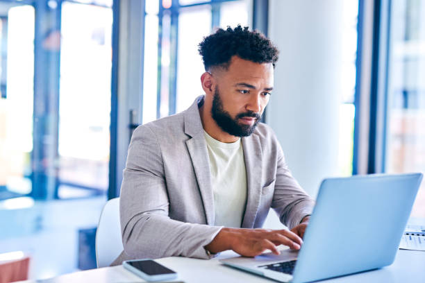 istock Shot of a young businessman using a laptop in a modern office at work 1367150119