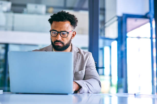 istock Shot of a young businessman using a laptop in a modern office at work 1367150128