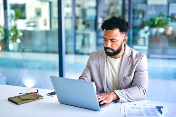 istock Shot of a young businessman using a laptop in a modern office at work 1367150144