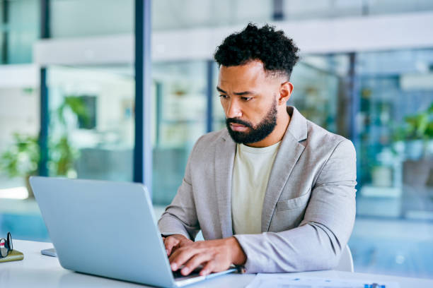 istock Shot of a young businessman using a laptop in a modern office at work 1367150149