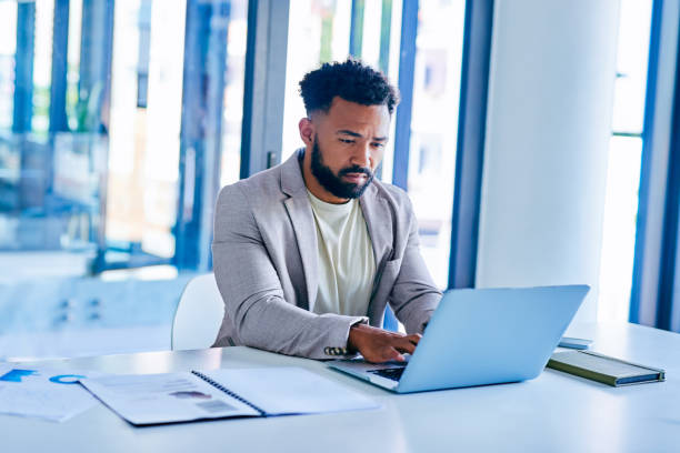 istock Shot of a young businessman using a laptop in a modern office at work 1367150231