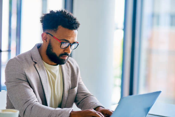 istock Shot of a young businessman using a laptop in a modern office at work 1367150252