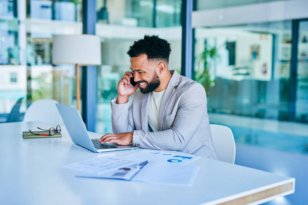 istock Shot of a young businessman using a laptop while on a call at work 1367150288