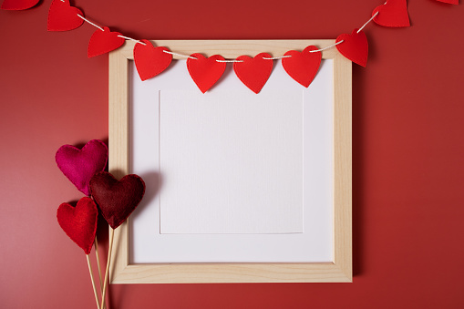 A white frame with a garland of red hearts with copy space. Background for the holiday. Love concept