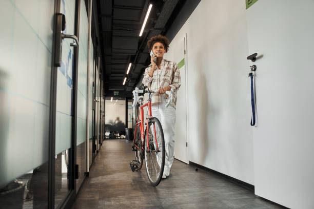 istock Multiracial curly woman having call at her smartphone while standing with her bicycle 1367152464