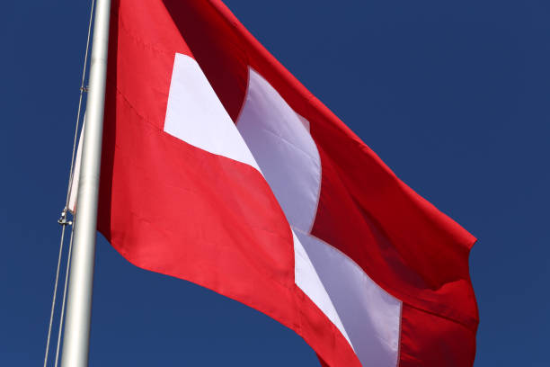 istock Swiss Flag with Blue Sky in the Background 1367153099