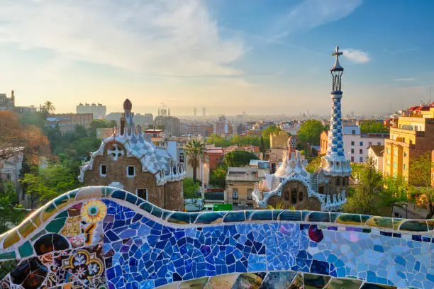 Barcelona city view from Guell Park with colorful mosaic buildings in tourist attraction Park Guell in the morning on sunrise. Barcelona, Spain