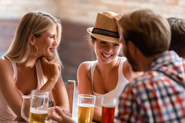 молодые пары пьют пиво и смеются вместе в баре - beer bar counter bar beer glass стоковые фото и изображения