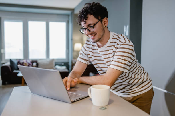 istock Young man uses laptop at home on the kitchen counter 1367155037