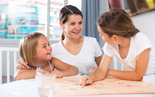 istock Mom with two daughters play board game at the table 1367155344