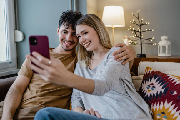 istock Young couple embracing at home and taking selfie 1367155488