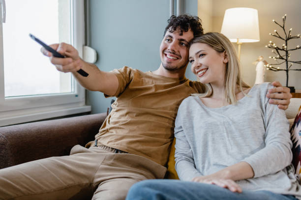 casal assistindo tv em casa - entertainment home interior electronics industry remote control - fotografias e filmes do acervo