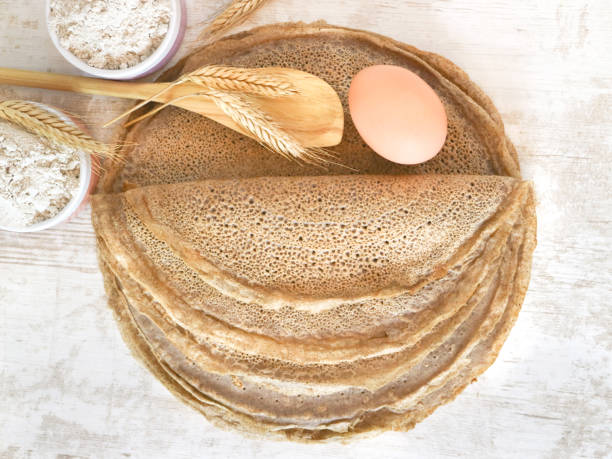 French buckwheat Galettes Bretonnes Top view of traditional French region of savory crepes Buckwheat Galettes Bretonnes with flour, wheat plant and egg on a wooden table. galette stock pictures, royalty-free photos & images