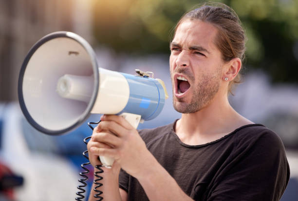 istock Shot of a young man using a megaphone at a protest rally 1367157820