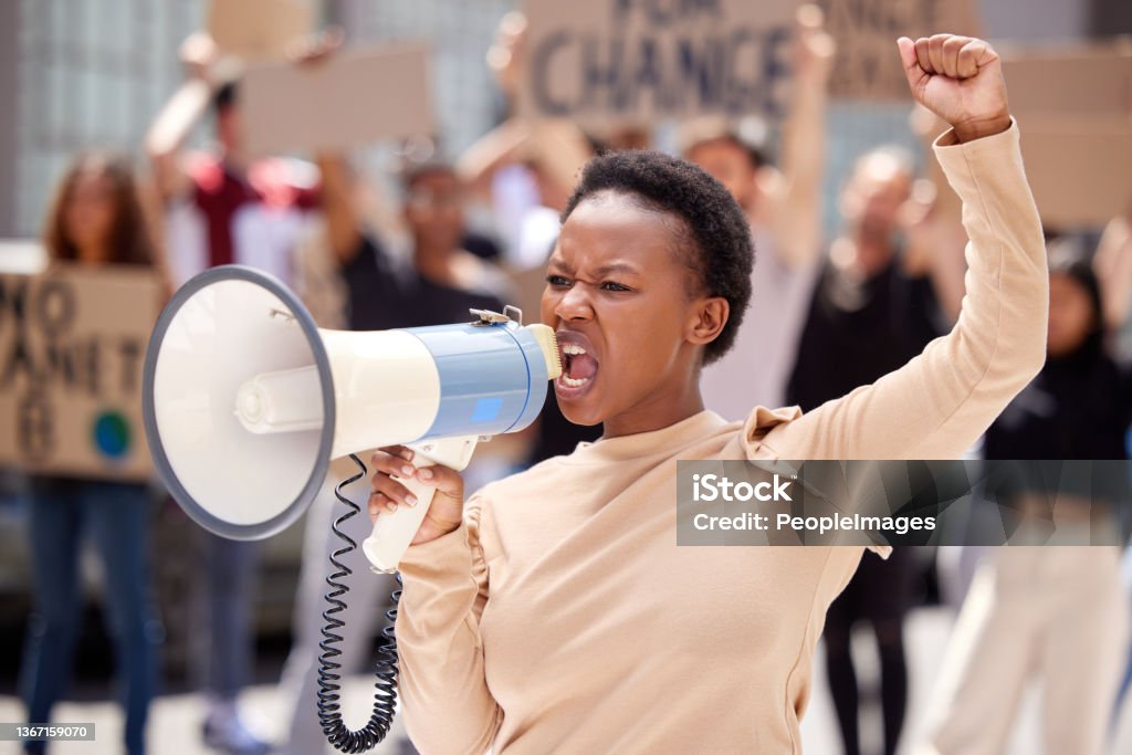 Shot of a young woman shouting through a loudhailer at a protest Fighting for the rights of others Protest Stock Photo