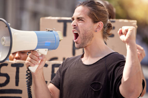 istock Shot of a young man using a megaphone at a protest rally 1367159086