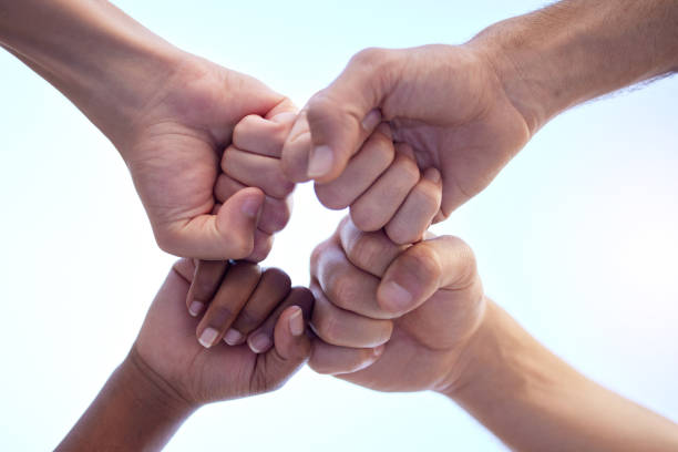 Shot of a group of people fist bumping one another in a circle Bringing the best of the best together anonymous activist network stock pictures, royalty-free photos & images