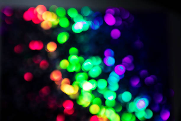 Trendy purple, green, pink circles bokeh festive glitter dark background with copy space. Christmas lights bokeh overlay pattern. Modern unicorn color abstract design
