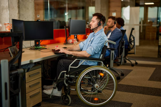 istock Handicapped computer programmer in wheelchair at his office desk 1367160570