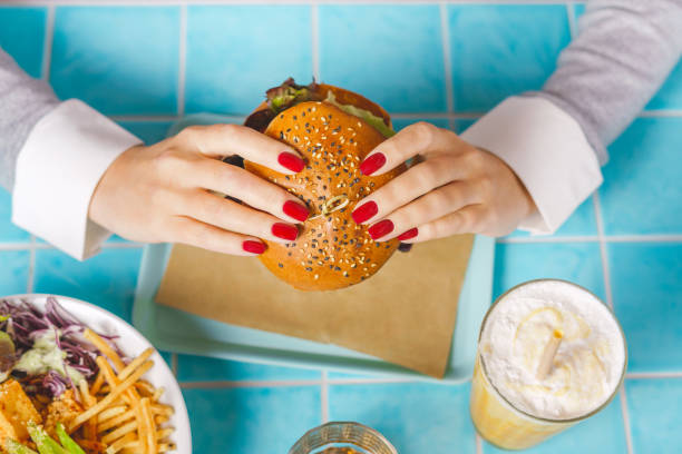 istock Woman eats a burger in a fast food restaurant 1367160888