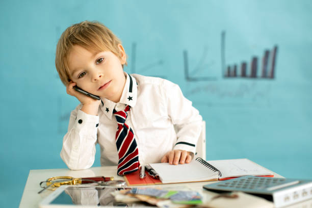 istock Good looking, smart casual dressed child, blond boy with tie, working on tablet, taking notes and talking on the phone, business concept 1367162998