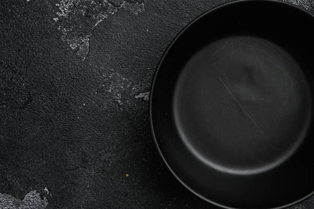 istock Black bowl, with copy space for text or food, with copy space for text or food, top view flat lay , on black dark stone table background 1367167760