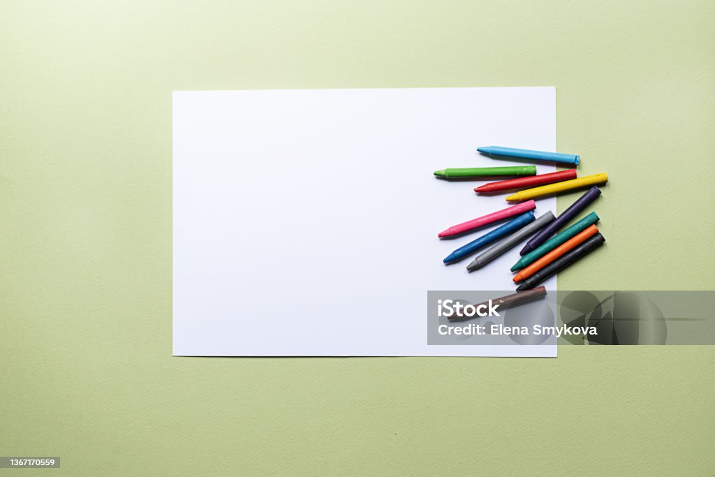 colorful crayons and blank paper colorful crayons and blank paper on the green background Crayon Stock Photo