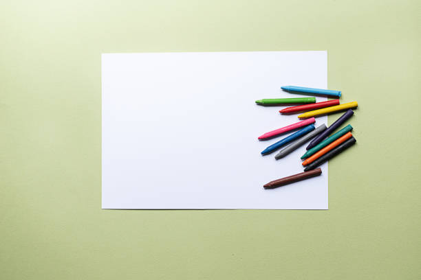 colorful crayons and blank paper colorful crayons and blank paper on the green background crayon photos stock pictures, royalty-free photos & images