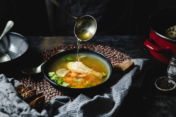 Serving chicken broth in soup bowl Cropped shot of pouring soup in bowl using ladle. Serving chicken broth in soup bowl over kitchen counter. chicken soup stock pictures, royalty-free photos & images
