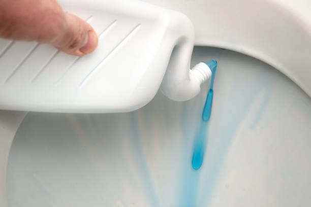 Male hand applying detergent liquid into a toilet bowl from a special bottle for toilet cleaning close up stock photo