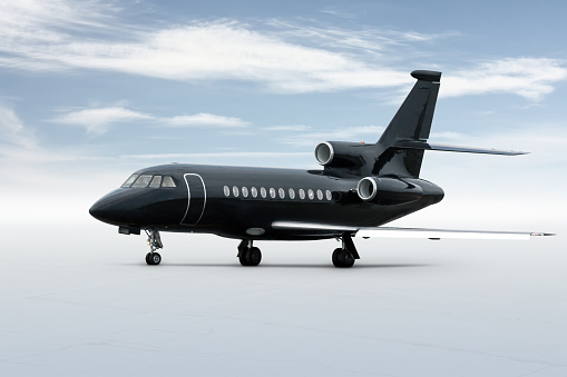 Modern black executive business jet isolated on bright background with sky