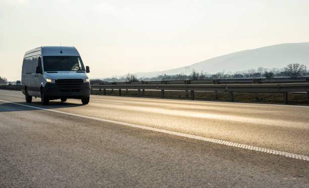 istock White modern delivery small shipment cargo courier van moving fast on motorway road to city urban suburb. 1367173406