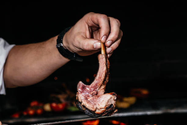 istock chef hands with raw fresh rack of lamb on grill background. Fired Barbecue, Restaurant menu, cookbook recipe 1367174760