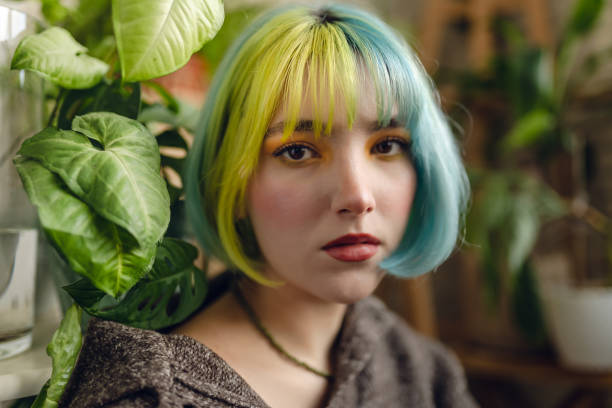 Portrait of beautiful young woman with colorful hair and make-up together with plants stock photo