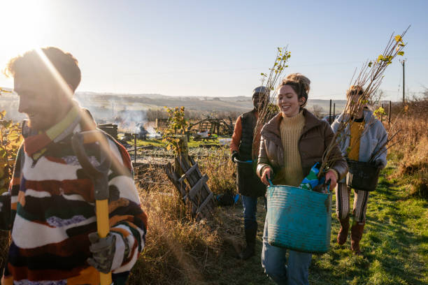 New Trees to Plant A group of volunteers wearing warm casual clothing and accessories on a sunny cold winters day. They are working in a field with young plants and trees on a community farm, planting trees and performing other sustainable and environmentally friendly tasks. walking for a cause stock pictures, royalty-free photos & images